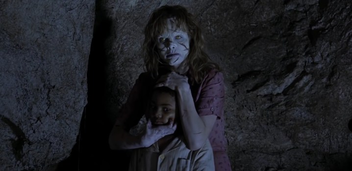 Uma Sarah possuída segurando uma criança em "Exorcista: O Começo".