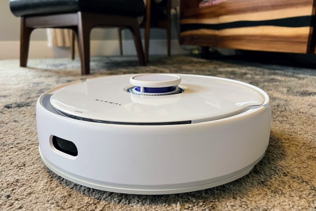A Narwal robot vacuum sits on a living room carpet.