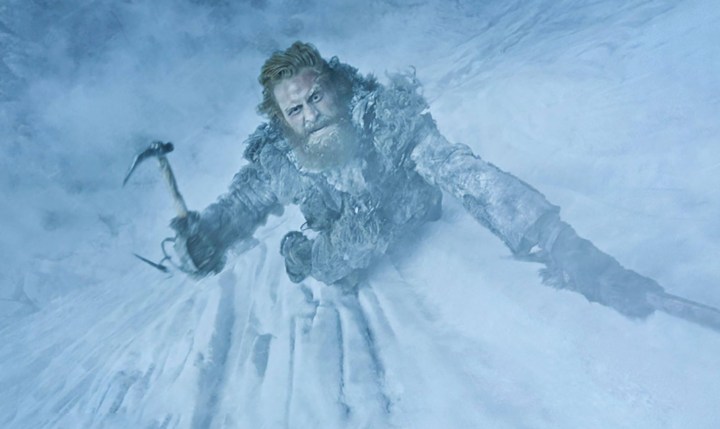 Un homme escalade un mur de glace avec une pioche dans Game of Thrones.