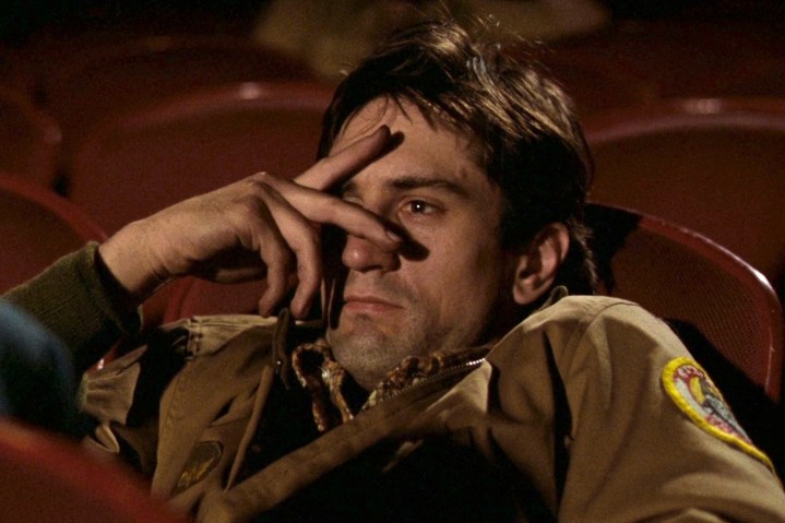 Robert De Niro se sienta en una sala de cine en Taxi Driver.