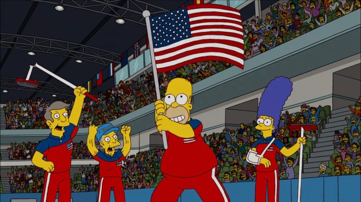 Homero ondeando la bandera estadounidense en los Juegos Olímpicos con Marge, Skinner y Agnes en "Los Simpson".