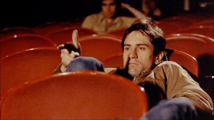 Travis Bickle sits in a theater in Taxi Driver.