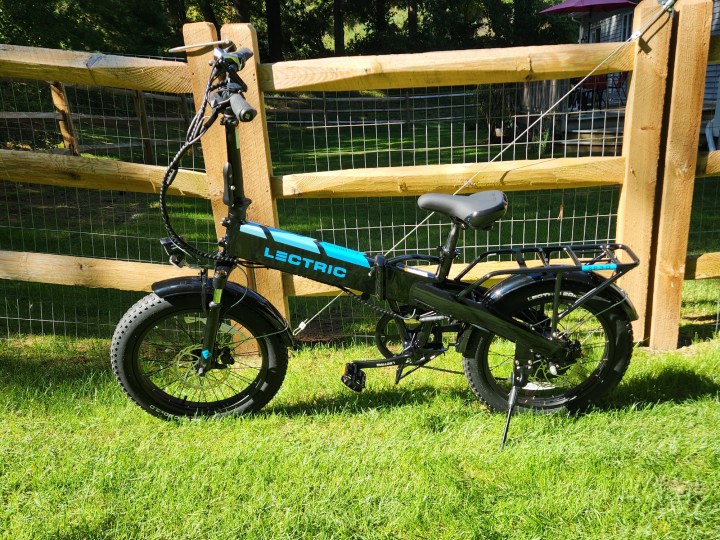 The Lectric XP 3.0 with standard equipment in front of a wood and wire fence is the best current vaue for a full-size, folding e-bike.