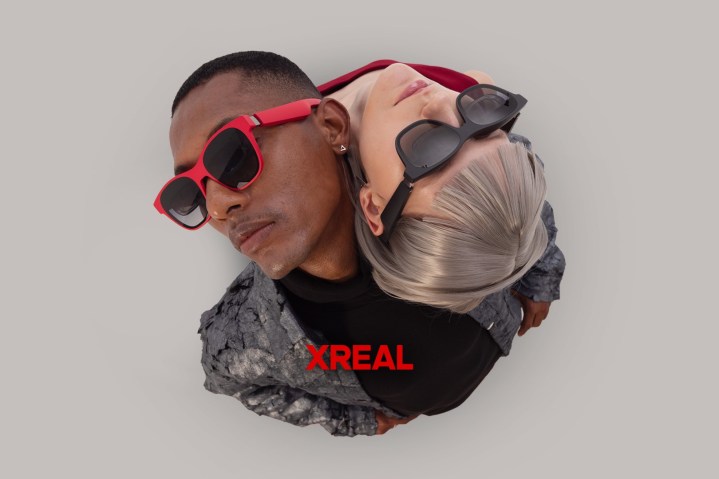 Two models lean heads on the other's shoulder to show Xreal Air 2 in black and red.