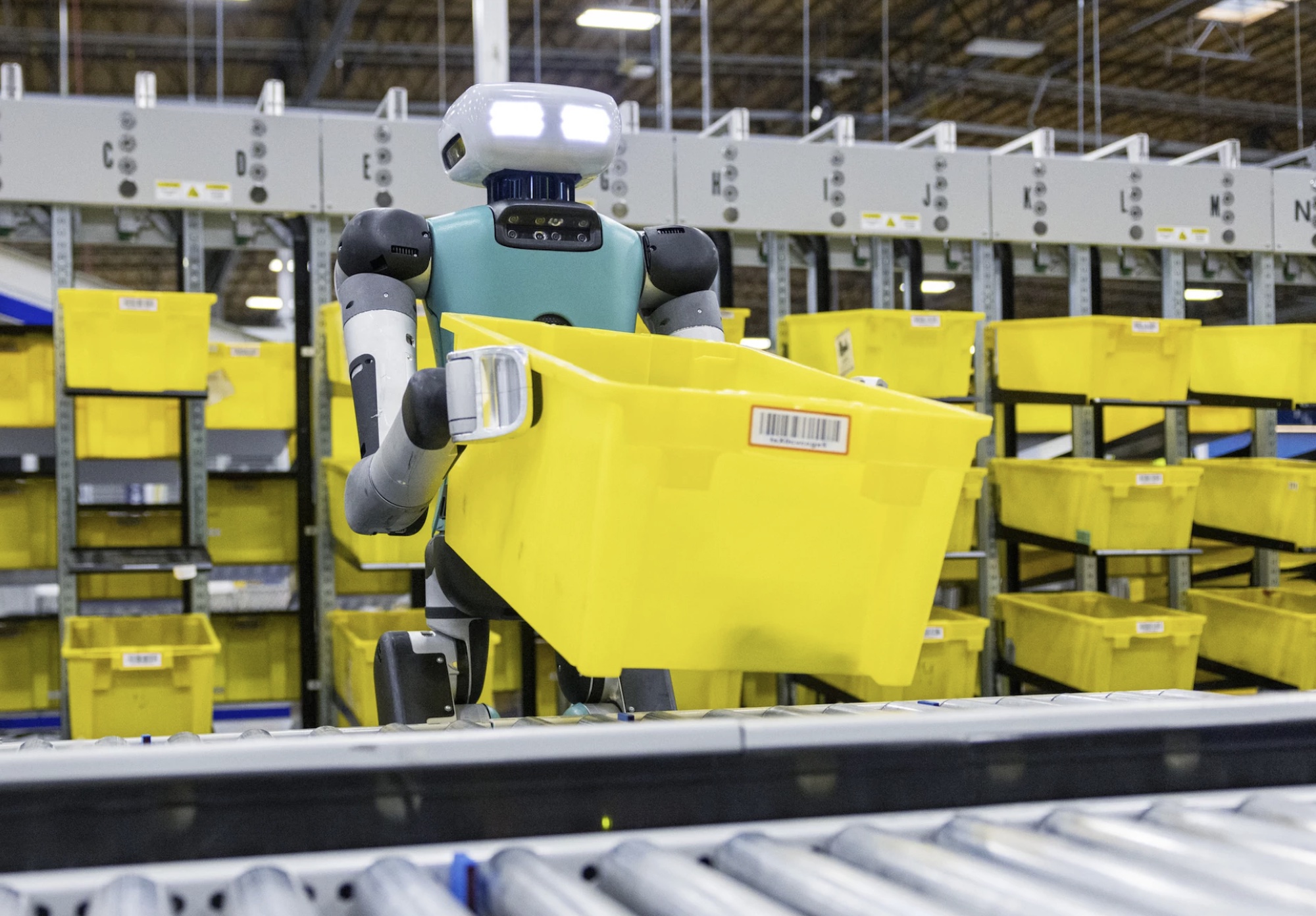 Amazon robot placing bin on roller belt.