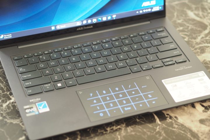 Asus Zenbook 14X OLED ऊपर से नीचे का दृश्य कीबोर्ड और एलईडी टचपैड दिखा रहा है।