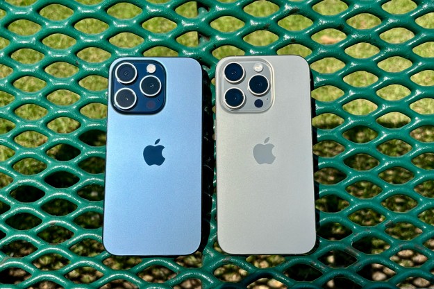 Blue Titanium (left) and Natural Titanium iPhone 15 Pros on a green park bench.