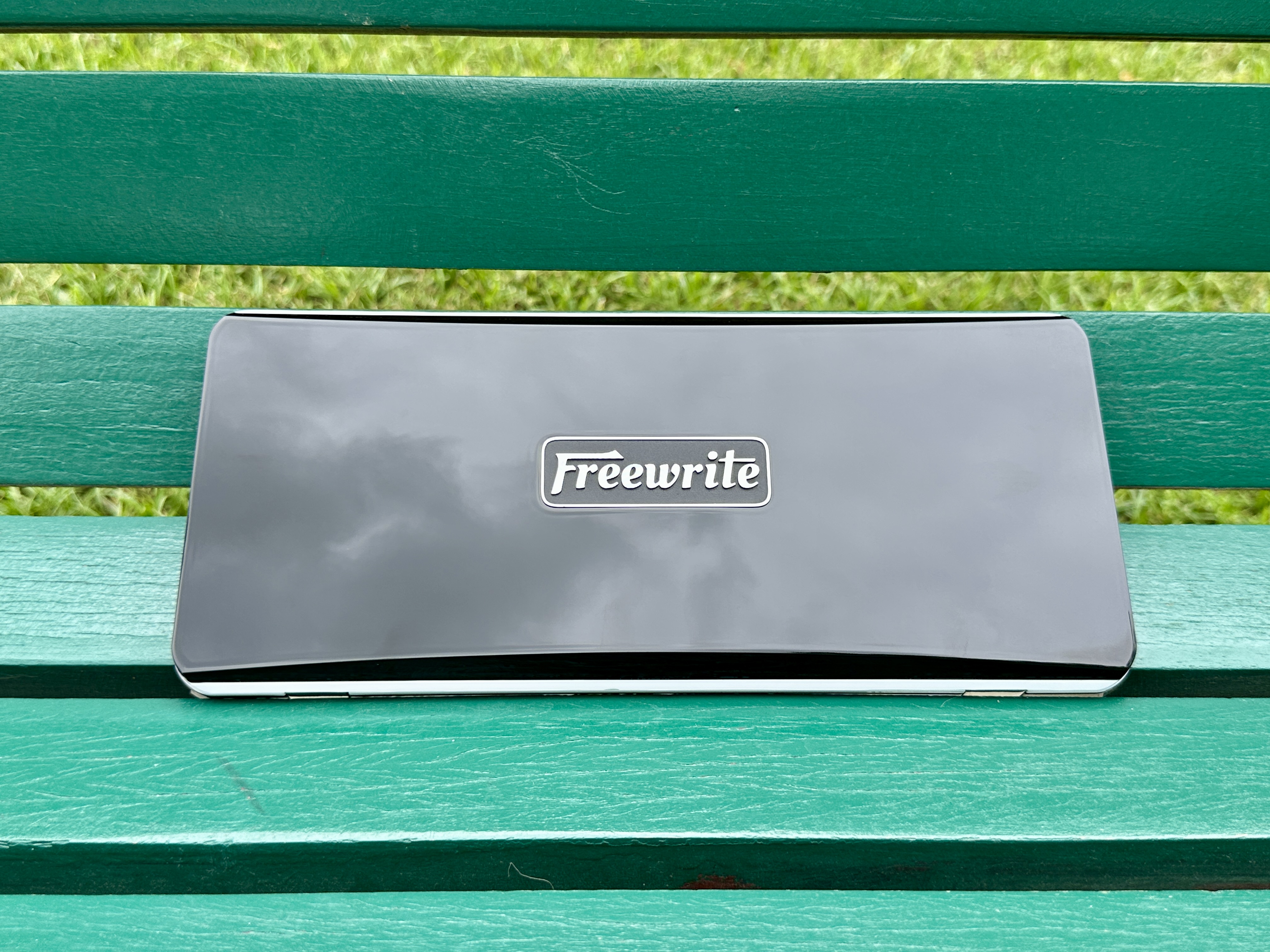 Freewrite Traveler closed on a green bench.