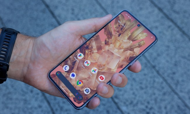 Holding the Google Pixel 8 Pro, showing its Home Screen.