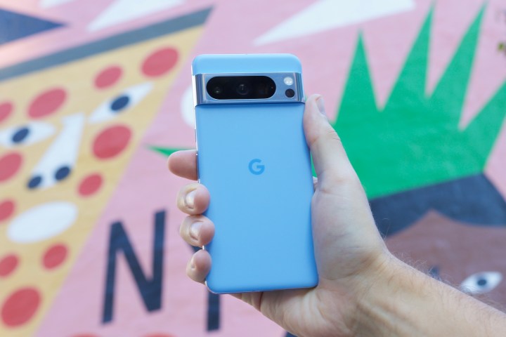 Someone holding the Google Pixel 8 Pro in front of a colorful mural.
