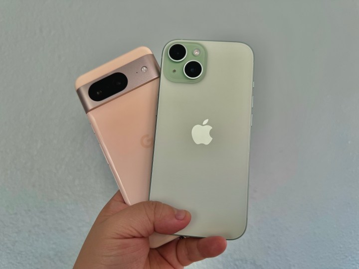A rose Google Pixel 8 (left) held in hand with a green iPhone 15.