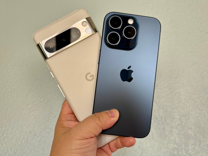 A Google Pixel 8 Pro in Porcelain (left) with an iPhone 15 Pro in Blue Titanium held in hand.