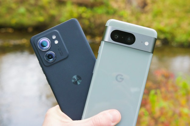 Someone holding the Motorola Edge (2023) next to the Google Pixel 8.