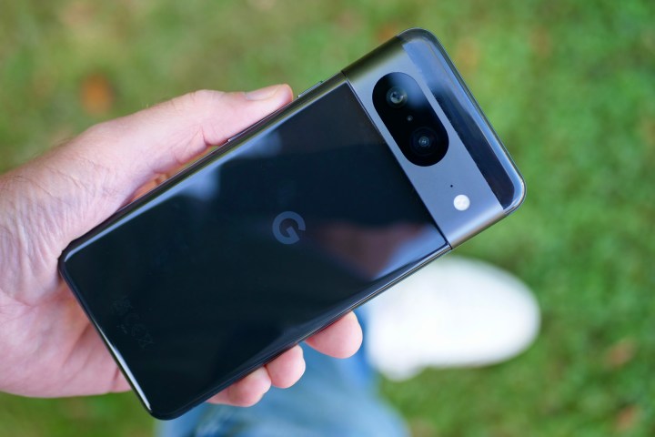 A person holding the Google Pixel 8, showing the back of the phone.