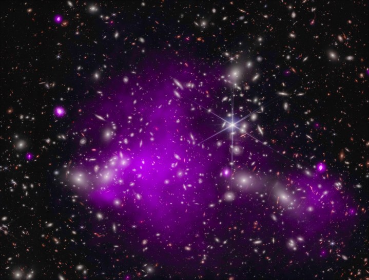 Les astronomes ont découvert le trou noir le plus éloigné jamais détecté en rayons X (dans une galaxie baptisée UHZ1) à l'aide des télescopes Chandra et Webb. L’émission de rayons X est une signature révélatrice d’un trou noir supermassif en pleine croissance. Ce résultat pourrait expliquer comment se sont formés certains des premiers trous noirs supermassifs de l’univers. Cette image composite montre l'amas de galaxies Abell 2744 derrière lequel se trouve UHZ1, dans les rayons X de Chandra (violet) et les données infrarouges de Webb (rouge, vert, bleu).