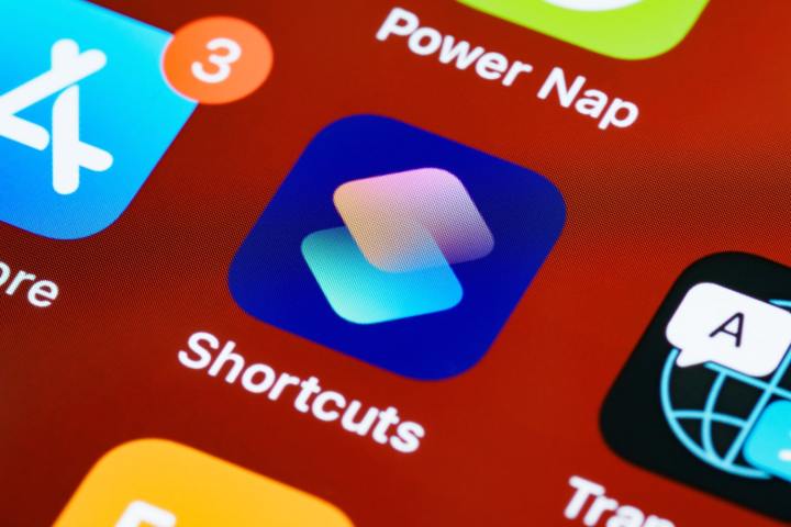 A close-up photo of the Shortcuts app on an Apple device, against a red background.
