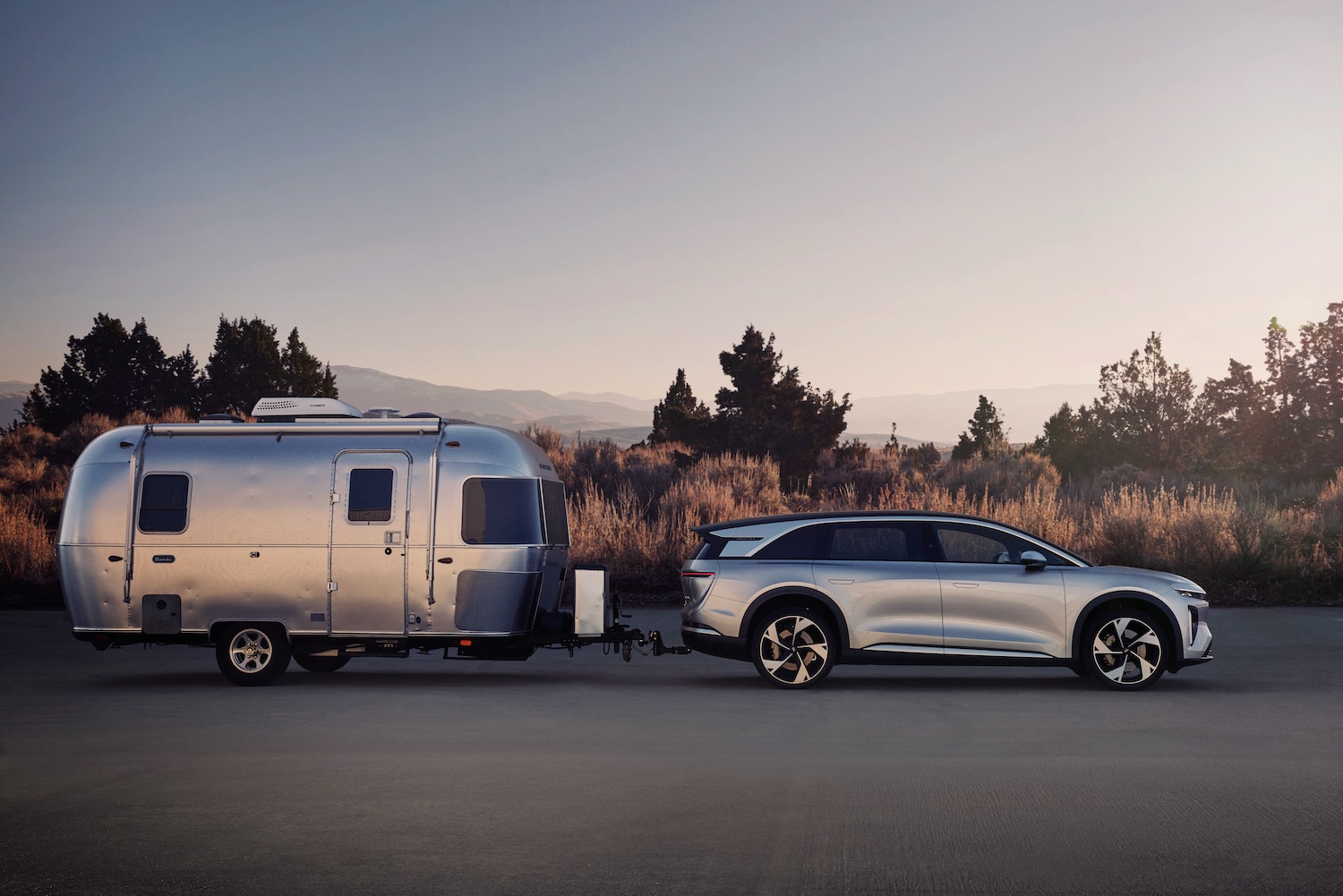 Profile view of a Lucid Gravity electric SUV towing an Airstream trailer.