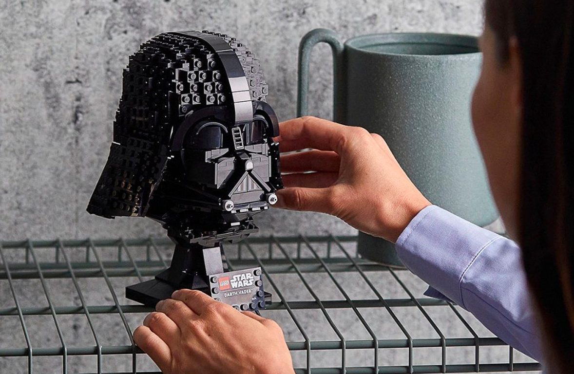 A woman puts the Lego Star Wars Dart Vader Helmet on a shelf.