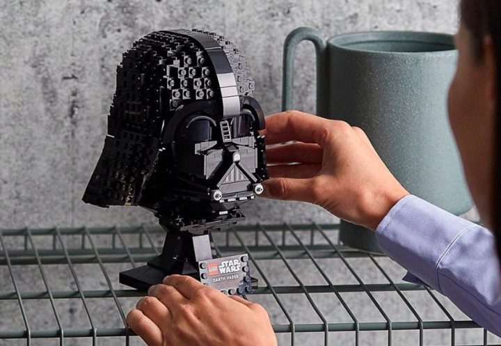 Una mujer pone el casco de Lego Star Wars Dart Vader en un estante.