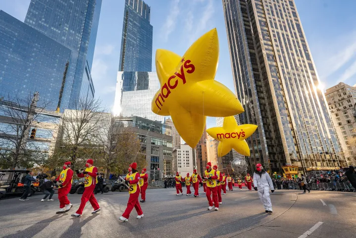 La gente marcha por las calles con un gran globo para el Desfile del Día de Acción de Gracias.