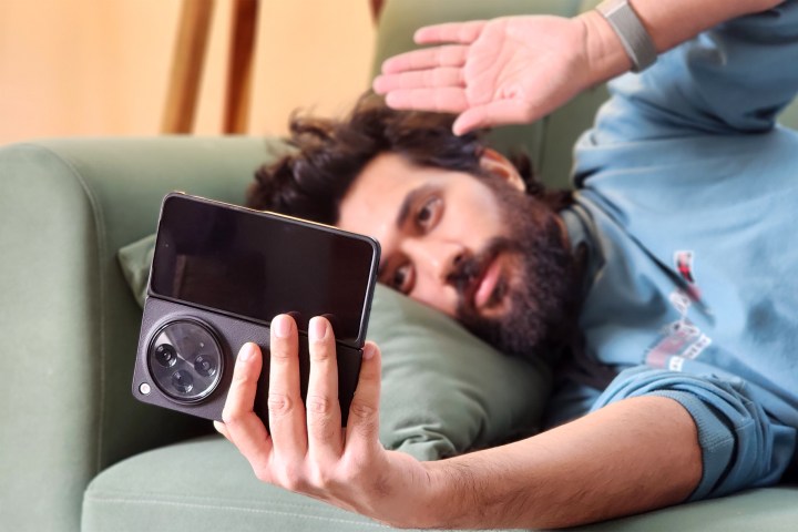 Man using OnePlus Open with air gestures while lying on a couch.