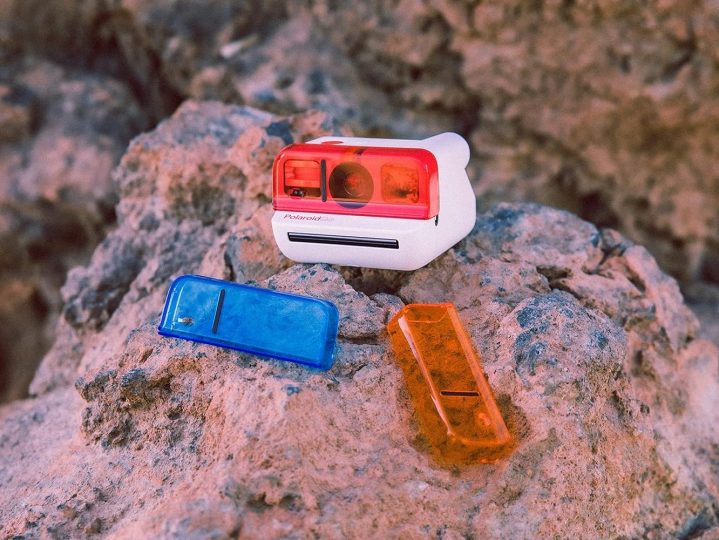 A Polaroid Go camera with lens accessories on a rock.