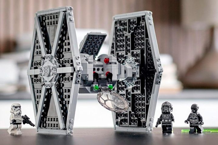 A pieced together Star Wars Imperial TIE Fighter Lego set with side characters on a table.