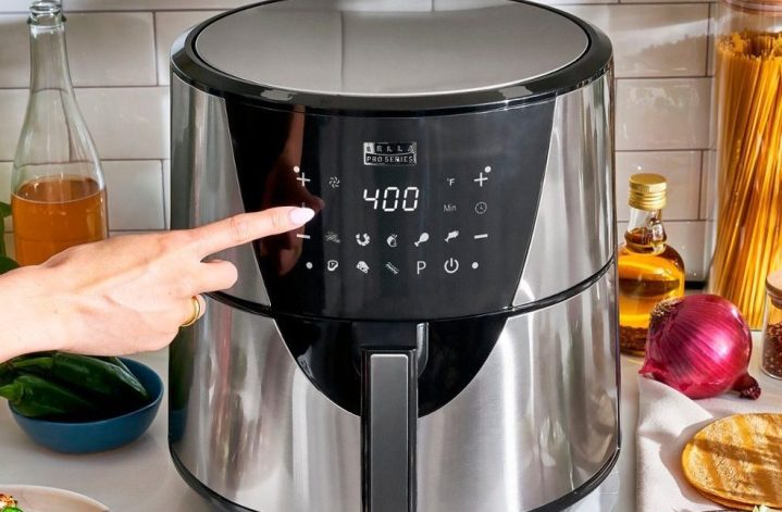 A woman taps the outside of the Bella Pro Series 8-quart Digital Air Fryer.