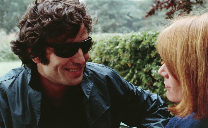 رجل يرتدي نظارة شمسية يتحدث إلى امرأة في فيلم The Strangler.