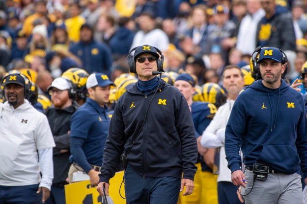 Jim Harbaugh walking down the sideline next to coaches.