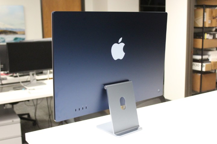 The back of a blue iMac on a white desk.