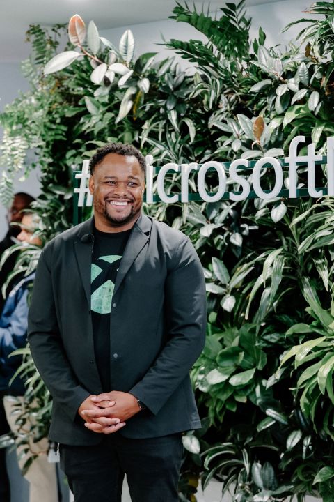 James Lewis stands in front of an Xbox logo.