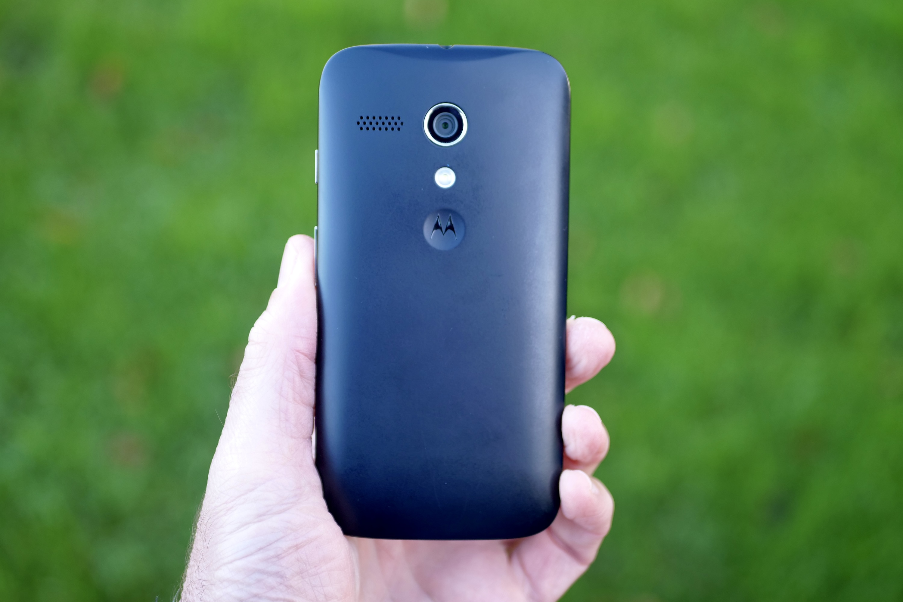 A person holding the Motorola Moto G, showing the back panel.