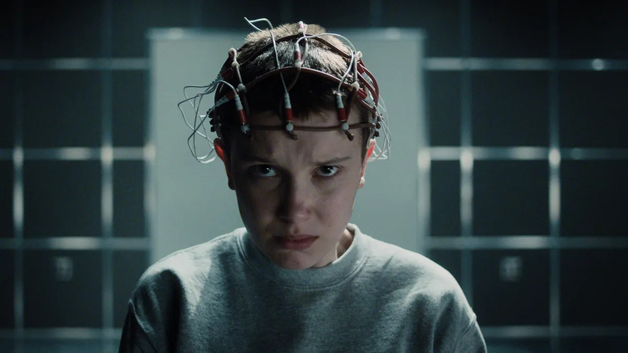 Eleven with modules on her head looking angry in a scene from Stranger Things.