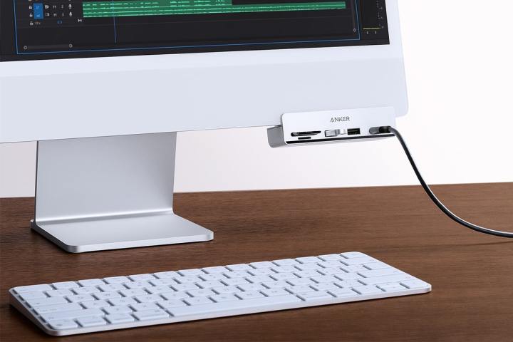 The Anker 535 USB-C Hub attached to the underside of an Apple iMac. There is an Apple Magic Keyboard on the desk in front of the iMac.