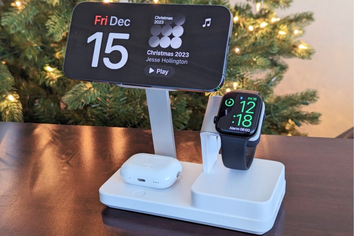 ESR 6-in-1 charging stand on table in front of a Christmas tree with iPhone 14 Pro Max docked in StandBy mode with Apple Watch Series 8 and AirPods Pro charging.