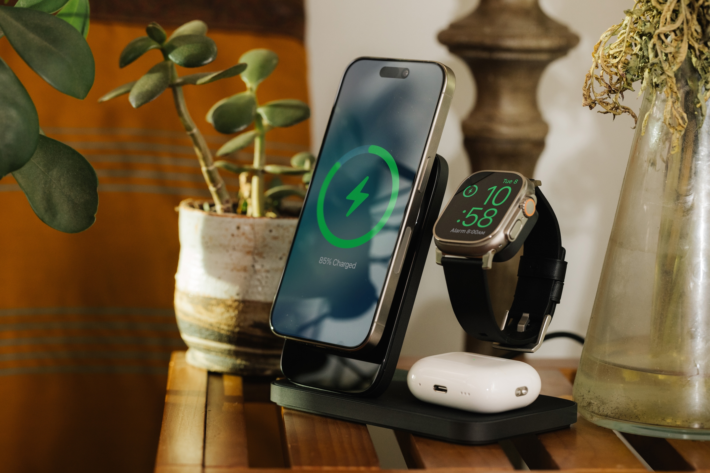 ब्लैक नोमैड स्टैंड वन मैक्स चार्जिंग स्टैंड घरेलू टेबल पर iPhone, Apple Watch Ultra और AirPods Pro के साथ डॉक किया गया है और चार्ज किया जा रहा है।