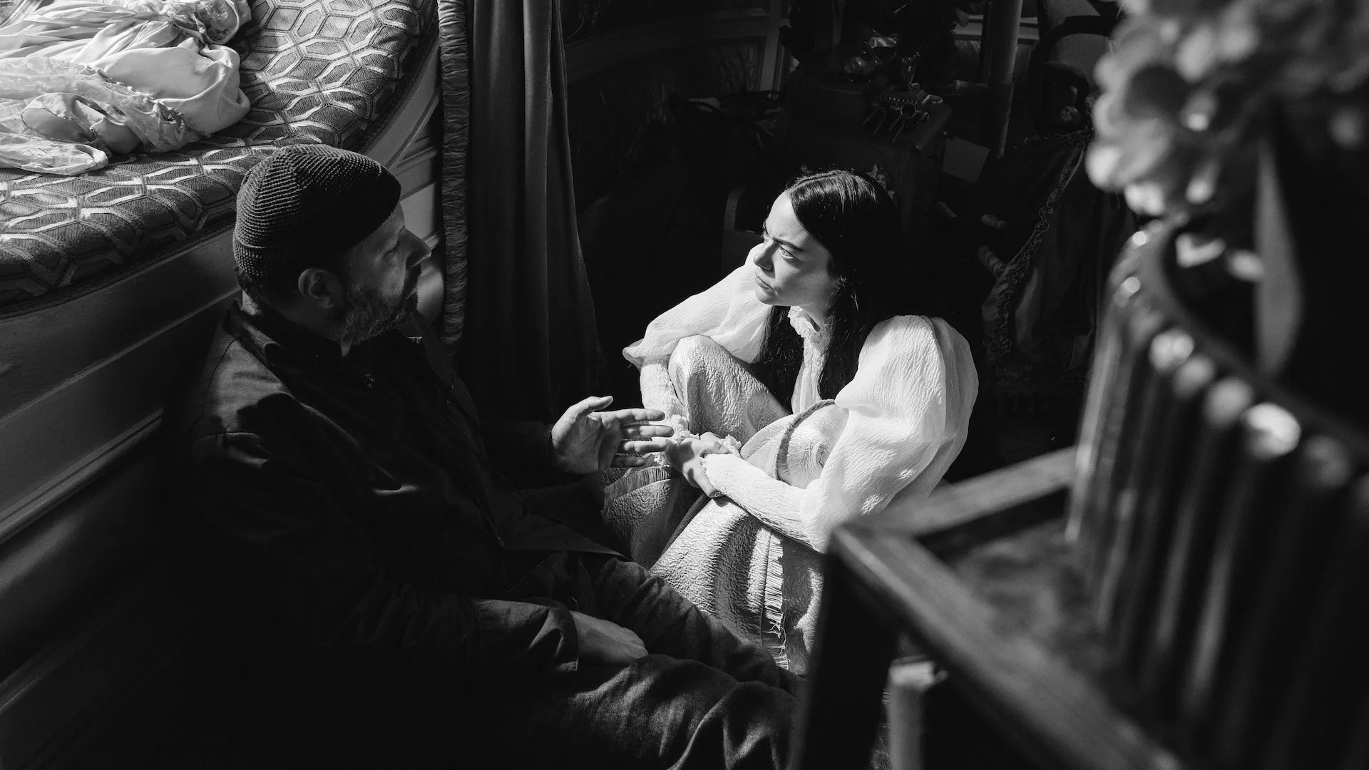 Un hombre habla con Emma Stone en el set de Poor Things.