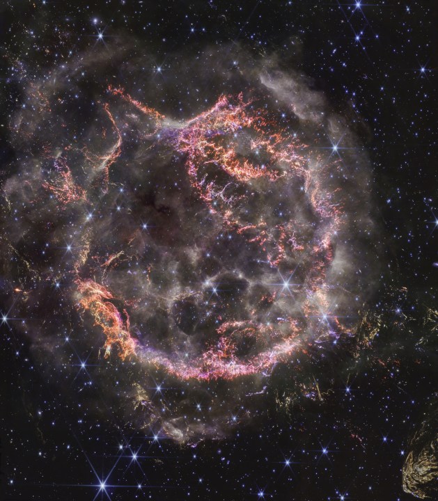 Una nueva imagen de alta definición de la NIRCam (Cámara de Infrarrojo Cercano) del Telescopio Espacial James Webb de la NASA revela detalles intrincados del remanente de supernova Cassiopeia A (Cas A), y muestra la capa de material en expansión que se estrella contra el gas arrojado por la estrella antes de que explotara. Los colores más notables en la imagen más reciente de Webb son grupos de naranja brillante y rosa claro que forman la capa interna del remanente de supernova. Estos diminutos nudos de gas, compuestos de azufre, oxígeno, argón y neón de la propia estrella, solo son detectables por la exquisita resolución de NIRCam, y dan a los investigadores una pista de cómo la estrella moribunda se rompió como un cristal cuando explotó.