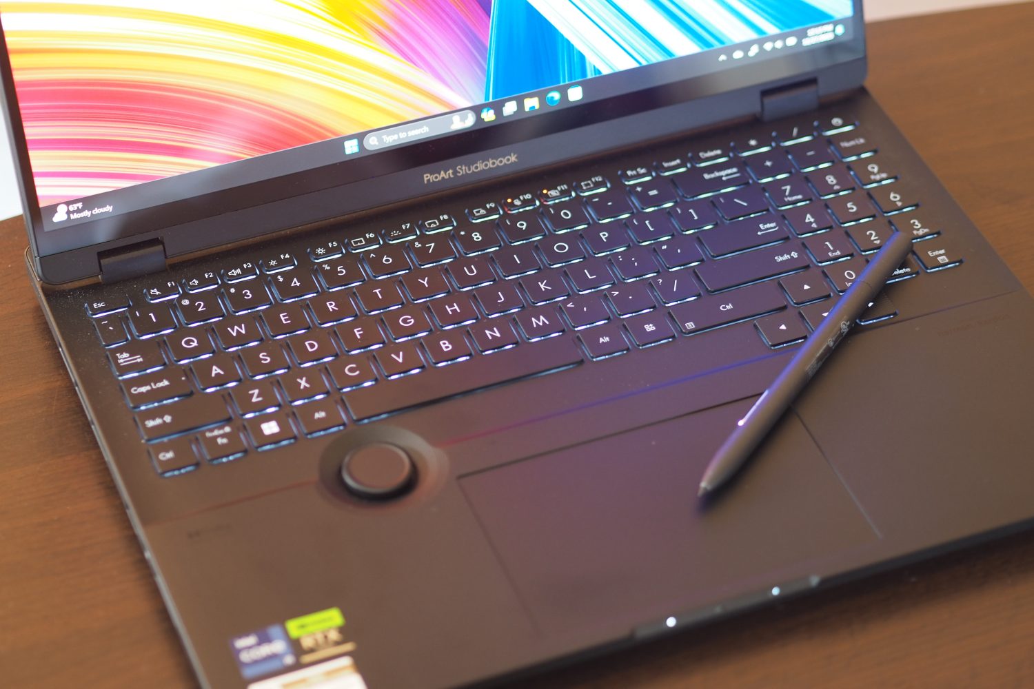 Asus ProArt Studiobook 16 OLED ऊपर से नीचे का दृश्य कीबोर्ड, टचपैड और पेन दिखा रहा है।