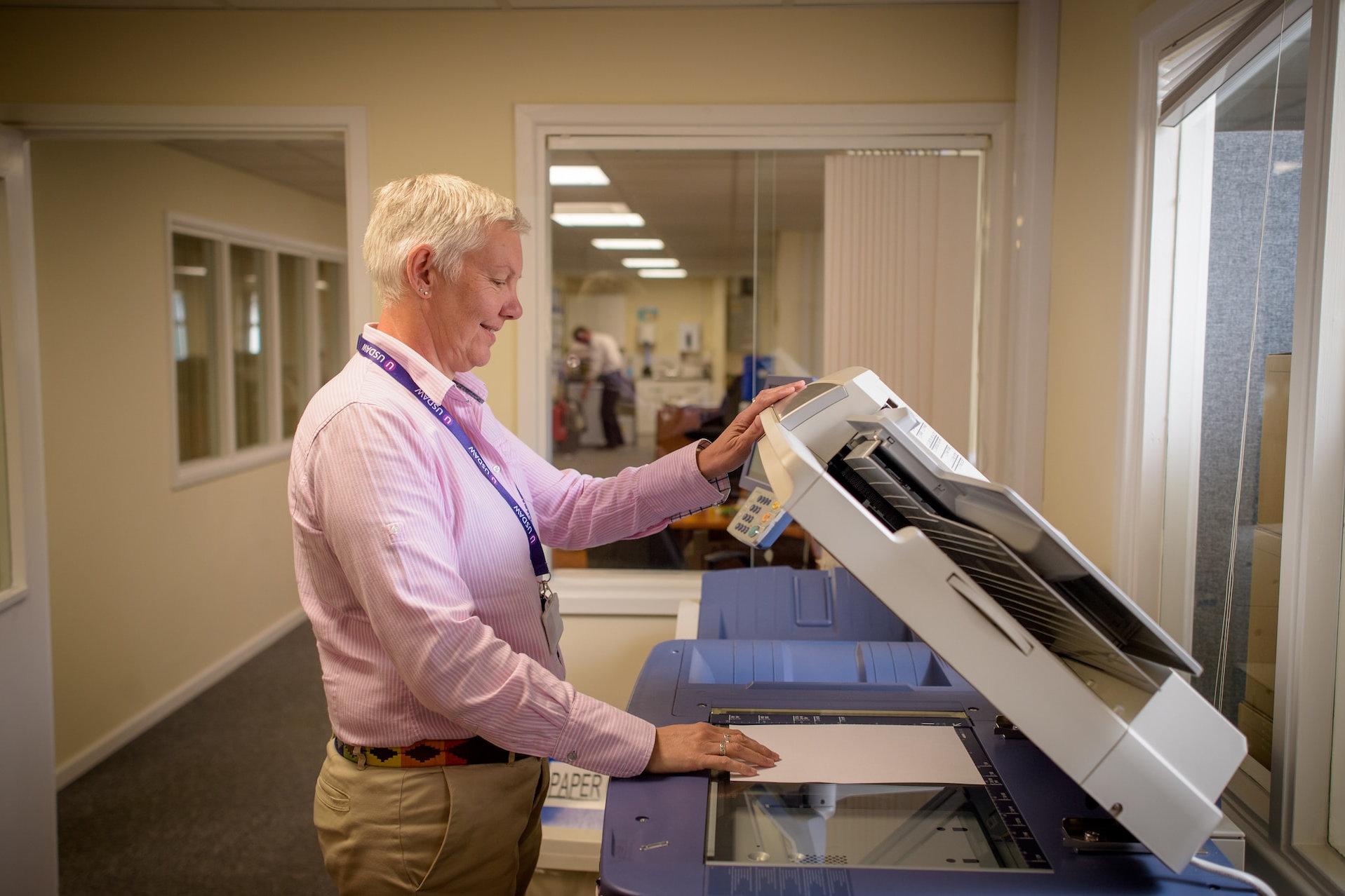 A person holds the lid and places a document in a large office copier.