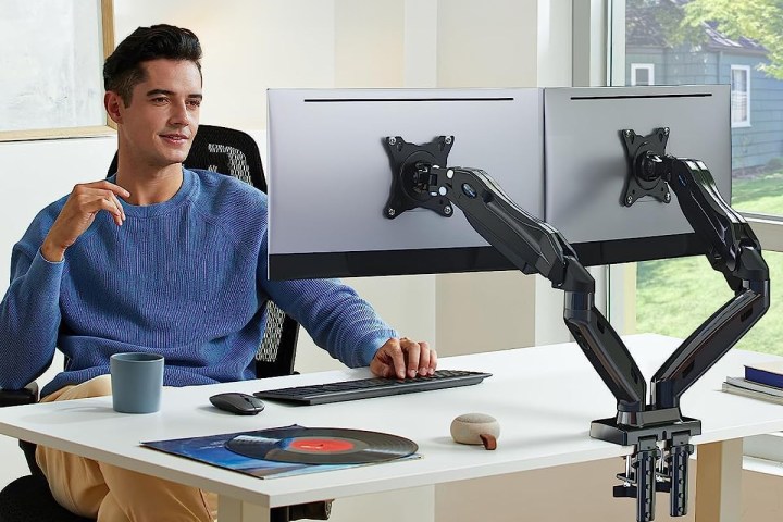 Man using dual monitor arms on his desk.