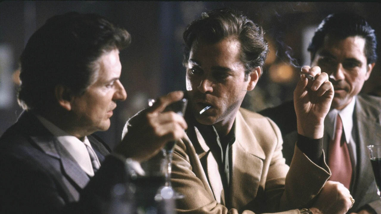 Tres hombres sentados en un bar bebiendo y fumando en una escena de Goodfellas.