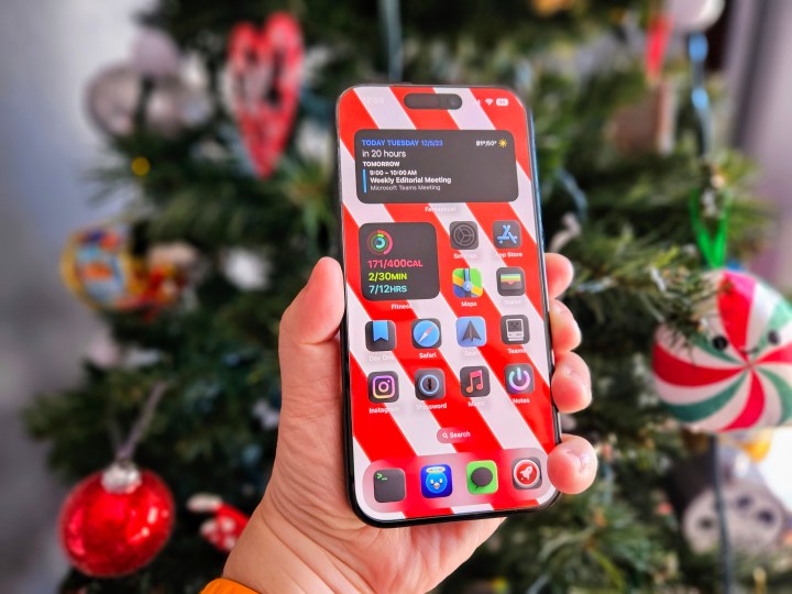 iPhone 15 Pro sostenido en la mano frente a un árbol de Navidad.
