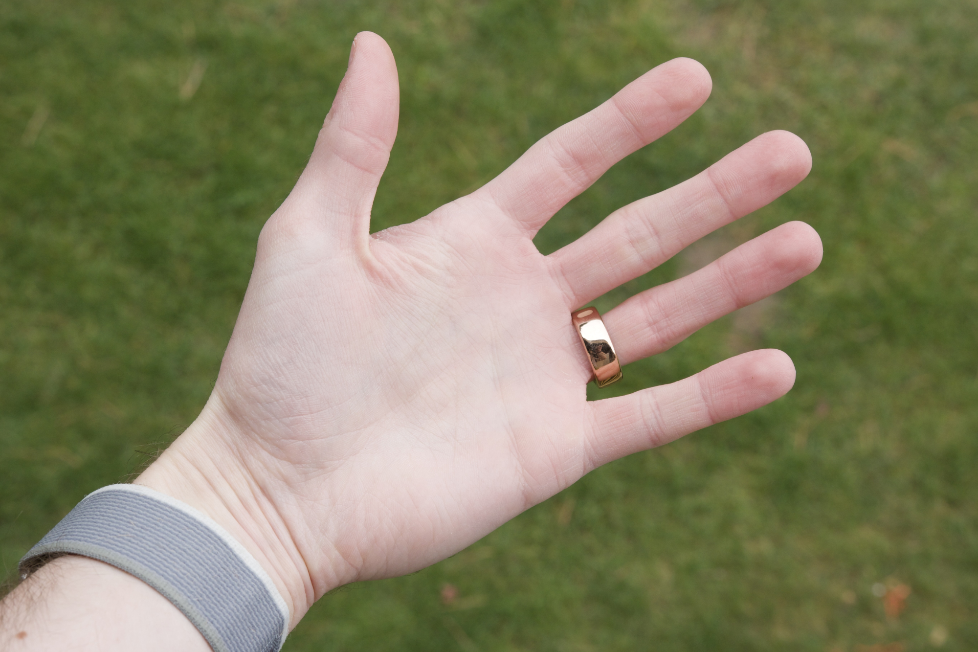 An Oura Ring Horizon, in rose gold, on someone's ring finger.