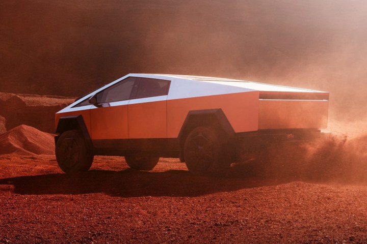 A Tesla Cybertruck throws red dust in a press photo.
