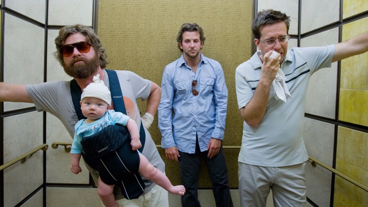 Akşamdan Kalma filminden bir sahnede asansördeki üç adamdan biri, biri ağzına bir bez kapatarak geriye yaslanmış, diğeri ise taşıyıcıda bir bebek tutuyor.
