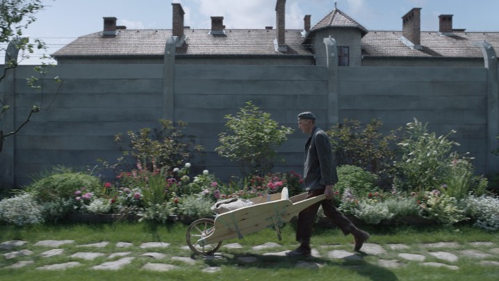 A man carries a wheelbarrow in The Zone of Interest.
