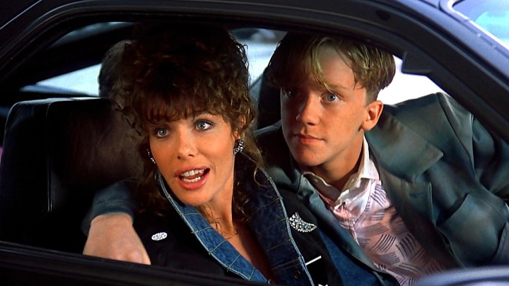 Weird Science filminden bir sahnede, araba kullanan genç bir genç, kolu muhteşem bir kadına sarılıyor.