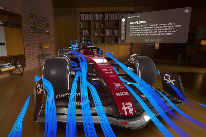 A rendering of a Formula One racing car appears with blue aerodynamic lines flowing over it in Apple's Vision Pro headset. The rendering is created using the JigSpace app.